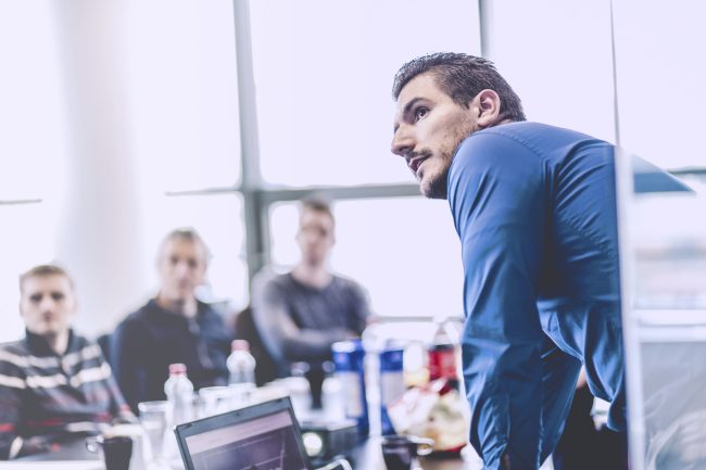 Zakenman die een presentatie op kantoor houdt. Bedrijfsleider die een presentatie aan zijn collega's tijdens vergadering of interne bedrijfstraining geeft, die bedrijfsplannen aan zijn werknemers uitlegt.