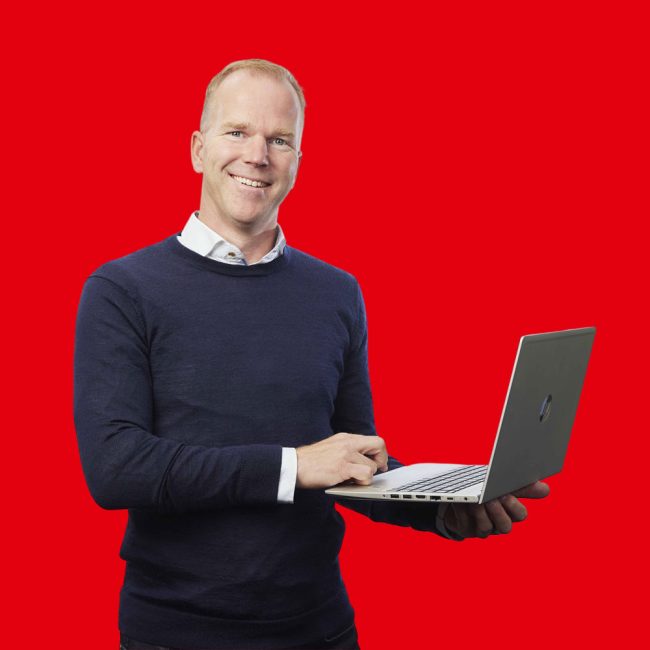 Berthil-Kranenborg heer met blauwe trui e witte blouse die lachend een laptop vast houdt
