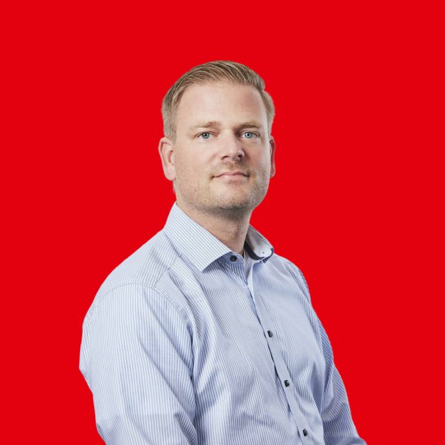 Mark-Nauta heer met blond haar en lichtblauwe blouse kijkt de camera in